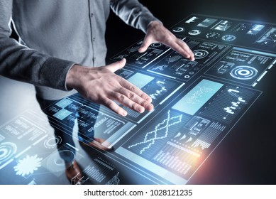 Controlling programs. Smart careful experienced programmer standing with his hands on the transparent screen and controlling the situation with a new program