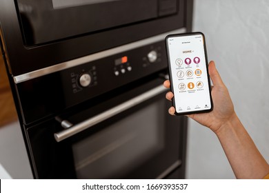 Controlling Smart Kitchen Appliance Using Mobile Phone At Home, Close-up On Mobile Screen. Concept Of A Smart Home And Managing Home With Mobile Devices