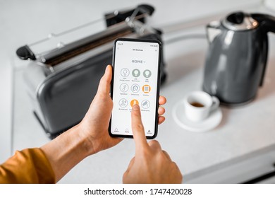 Controlling Smart Kitchen Appliance Using Mobile Phone At Home, Close-up On Mobile Screen. Concept Of A Smart Home Devices