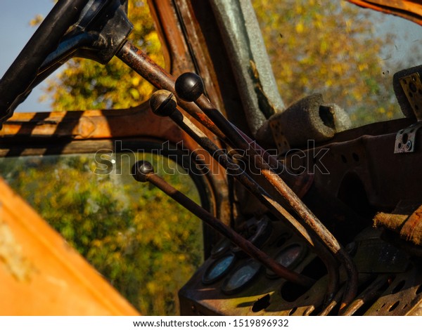 Controls the old tractor.\
Steering wheel and levers at the rusty tractor. Old agricultural\
machine
