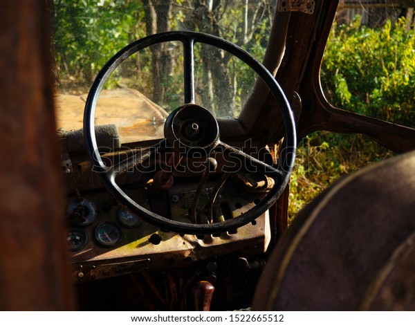 Controls the old tractor.\
Steering wheel and levers at the rusty tractor. Old agricultural\
machine