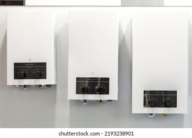 Convection Gas Boilers Of White Color On A White Wall Of Different Sizes. A Stand With White Models Of Boilers Of Different Sizes.