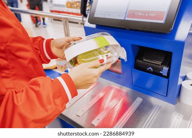 convenience of a modern shopping as a customer scans their own items at the self-service checkout in a bustling supermarket.