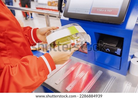 convenience of a modern shopping as a customer scans their own items at the self-service checkout in a bustling supermarket.