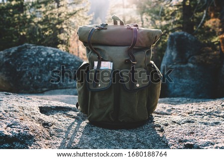 Convenient backpack with map equipment for active leisure tourism in national park with forests, khaki rucksack with roll top and pockets for transporting stuff on hiking