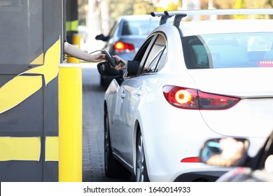 Convenient payment from car, drive thru system. Payment for services credit card using pos terminal. Customer purchases goods without leaving his car. Drivers are charged certain fare. - Shutterstock ID 1640014933