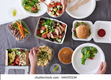 Convenient takeaway takeout food for party, overhead spread of assorted food with hands serving up