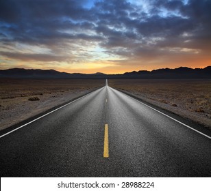 Converging Lines Of A Blacktop Highway And Mountains At Sunset In The Desert, Death Valley National Park, California, USA