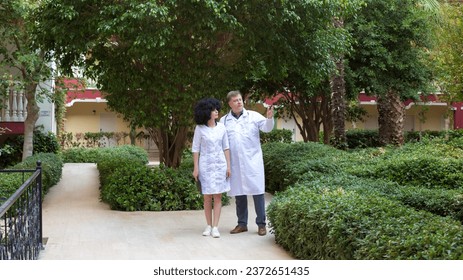Conversation between two doctors courtyard of a clinic with a green garden.