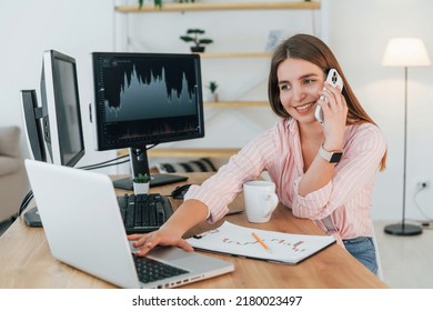 Conversation By The Phone. Female Stockbroker In Casual Clothes Is Working In The Office By Pc.