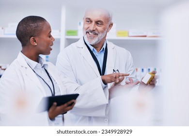 Conversation, tablet and pharmacists checking medication for inventory, stock or medical research. Healthcare, medicine and senior chemist mentor teaching female pharmaceutical student with tech. - Powered by Shutterstock