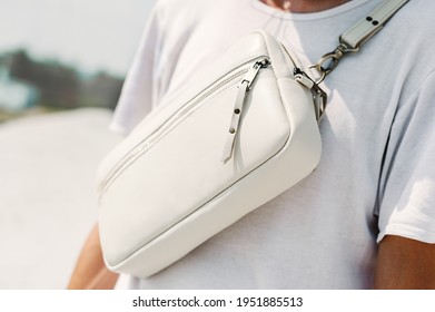 Convertible Belt Bag Leather. A Guy In A White T-shirt And A White Leather Bag Is Standing In The Street. Fanny Pack Close Up.
