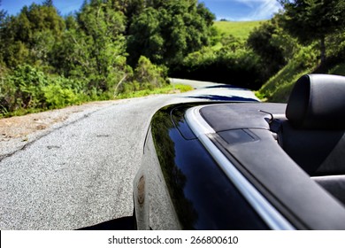 Convertible Car Driving On A Winding Road On A Sunny Summer Day