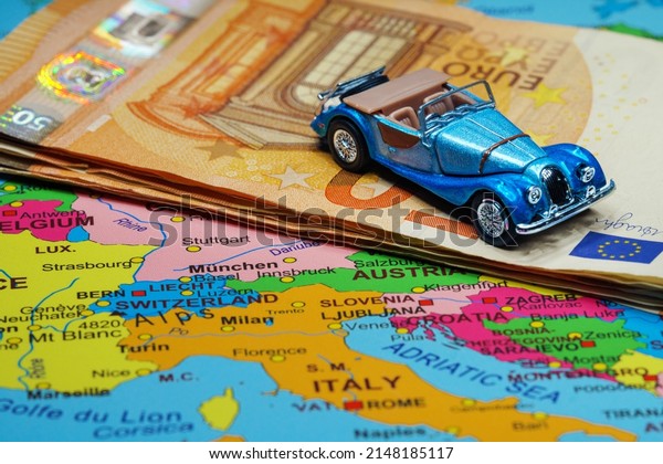 Convertible\
car and euro banknotes on a map of\
Europe.