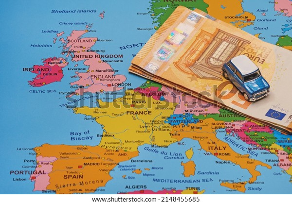 Convertible\
car and euro banknotes on a map of\
Europe.