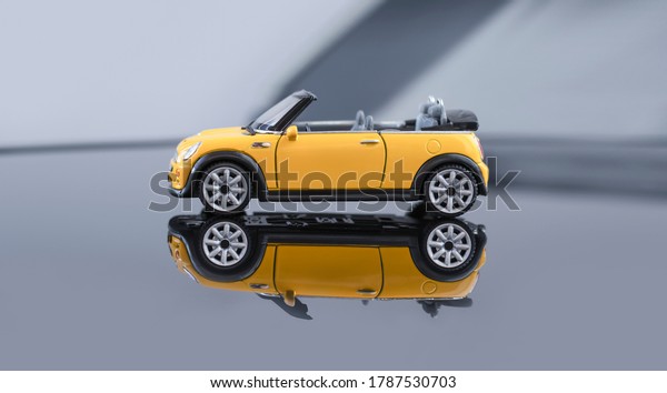 Convertible model yellow Mini Cooper. A yellow toy\
car rides on a light background, reflected on a mirrored floor.\
July 31, 2020, Belarus\
Gomel.