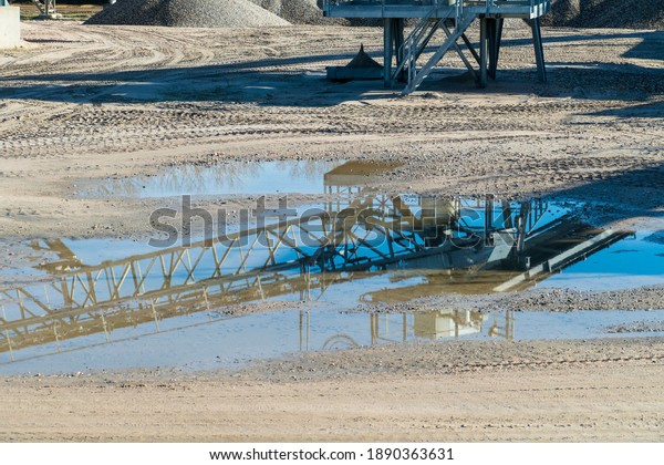Conveyor belt and crane are reflected on the surface\
of the lake