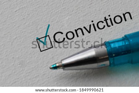 Conviction - checkbox with a tick on white paper with pen. Checklist concept.