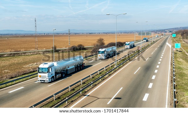 Convoy or Caravan of Tank trucks or cisterns on\
a Highway through the rural landscape. Business Transportation And\
Trucking Industry.