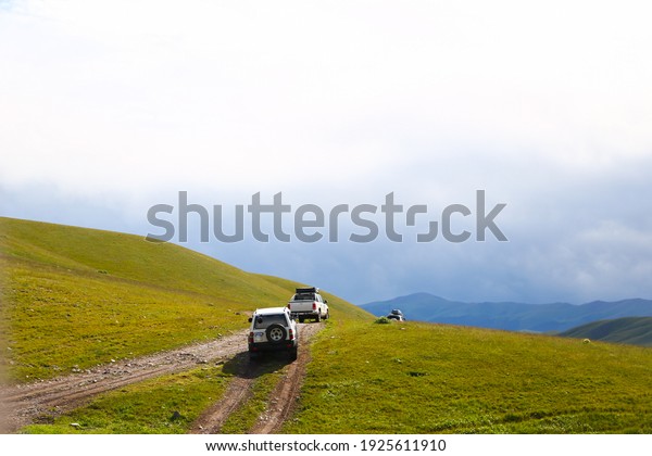 a convoy of cars is moving along a dirt road.\
travel by car in the mountains. rough road in the steppe. jeeps\
make their way through the\
desert