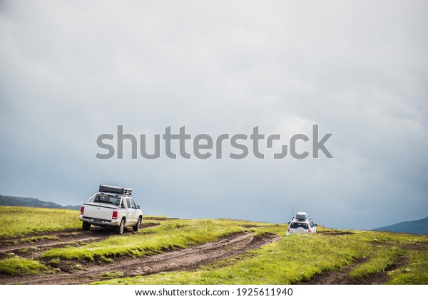 a convoy of cars is moving along a dirt road.\
travel by car in the mountains. rough road in the steppe. jeeps\
make their way through the\
desert