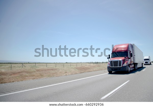 Convoy of powerful modern semi-trucks with\
various types of semi trailers for transporting wide range of\
manufactured goods products and food through a network of highways\
connecting whole of\
America