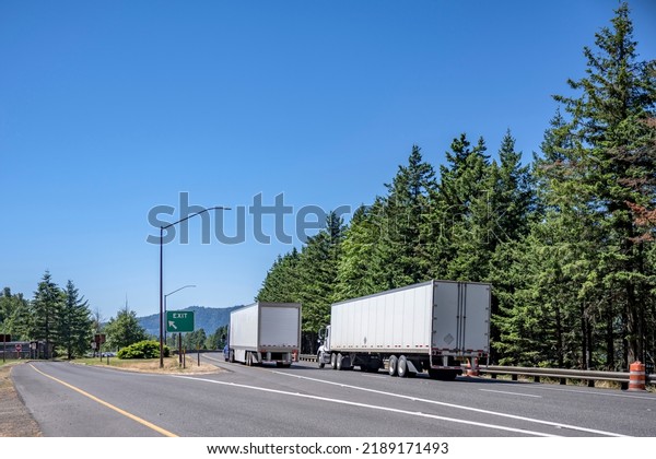 Convoy Of Tow Different Industrial Freight Big Rigs Semi Trucks With Dry Van Semi Trailers