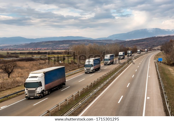 Convoy of\
transportation  trucks in line as a caravan or convoy on a country\
highway under an amazing blue\
sky