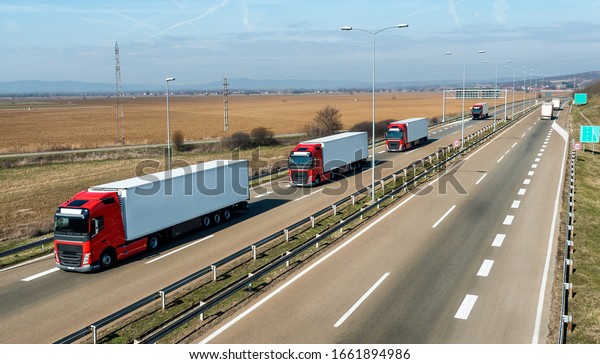 Convoy of\
transportation trucks passing on a highway on a bright blue day.\
Highway transportation with white lorry\
tracks