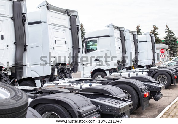 A convoy of truck tractors\
stands at a service parking lot. Truck service concept,\
industry