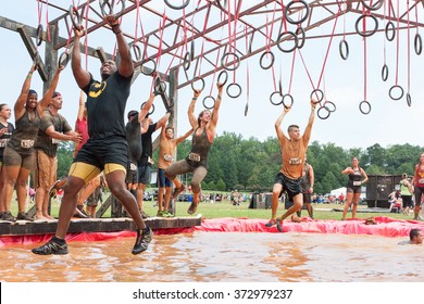 CONYERS, GA - AUGUST 22:  Competitors Try To Cross A Muddy Pool Of Water By Swinging From Rings At An Amateur Obstacle Course Race Open To The Public On August 22, 2015 In Conyers, GA. 