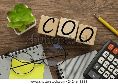 COO text representing Chief Operating Officer text on wooden blocks. near the calculator
