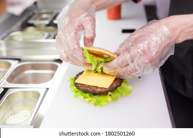 Cook adding a second half of the burger. Preparing burger in restaurant. Hands of the cook in disposable gloves based on hygiene requirements. - Powered by Shutterstock