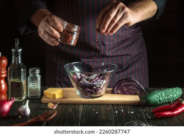 The cook adds aromatic seasoning to vegetarian food. Cooking delicious salad by the hands of the chef in kitchen. Menu idea for a hotel or restaurant
