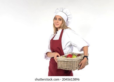 Cook with basket of fruits. Wicker basket in hands of woman chef. Girl chef in restaurant. Restaurant chef on light background. Cook confectioner with fresh fruit. Concept - cooking fruit dishes - Powered by Shutterstock