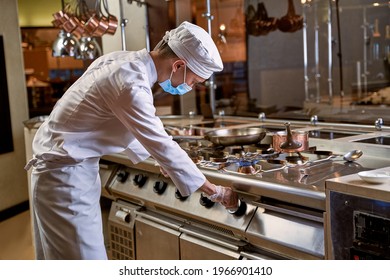 Cook Bending Over Stove While Turning A Knob