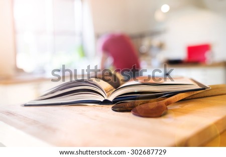 Cook book laid on a kitchen table with two wooden spoons