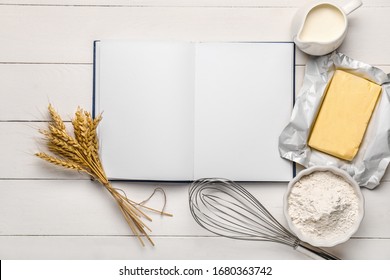 Cook book with products on white wooden background