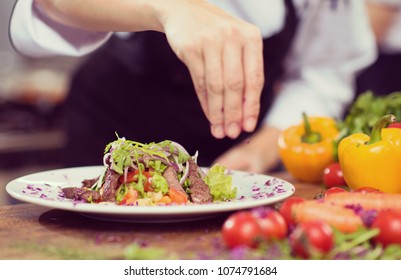 cook chef decorating garnishing prepared meal dish on the plate in restaurant commercial kitchen - Powered by Shutterstock