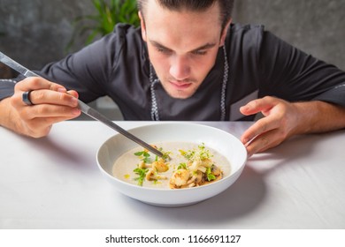 Cook Chef Making Creme Soup With Herbs, Mushrooms, Scallops And Toast Bred.