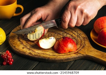 The cook cuts apples on a cutting board to make compote or fruit juice. Apple diet for a set of vitamins