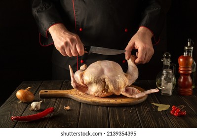 The Cook Cuts Raw Broiler Chicken With A Knife. Cooking A National Dish In The Restaurant Kitchen With Chicken.