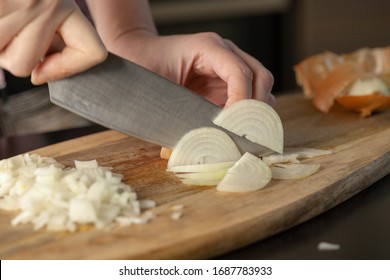 The cook cutting and dice onion on a wooden chopping board. Closeup.