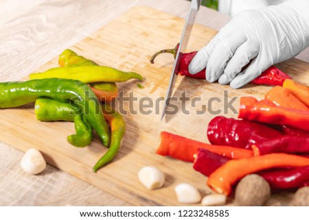 cook cutting hot chili peppers on a wooden board 