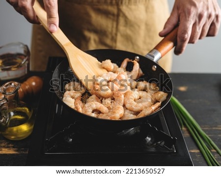 Cook hands cooking big tiger shrimps and frying on wok pan, close up steps recipe on kitchen background 