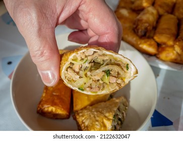 The Cook Holding A Half Cut Home Made Crispy Spring Roll Showing The Meat And Vegetable Filling Inside.