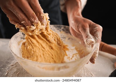 Cook kneaded yeast dough with his hands in a deep glass bowl. Close-up - Powered by Shutterstock