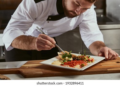 Cook man neatly decorates the dish. young professional chef adding some piquancy to meal. in modern kitchen, at work in uniform - Powered by Shutterstock