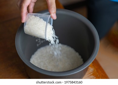 The cook measured the rice with a measuring cup to cook the rice.