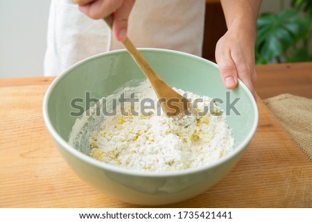 Cook mixing ingredient and wheat flour with wooden spoon in ceramic bowl. Dough preparation for homemade pastry and bread. Studio shot. Side view. Cooking and baking at home concept